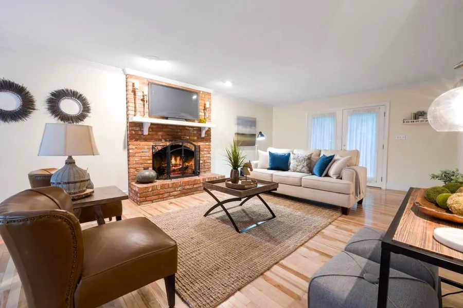 Lit brick fireplace in a New Jersey suburban living room with hardwood floors